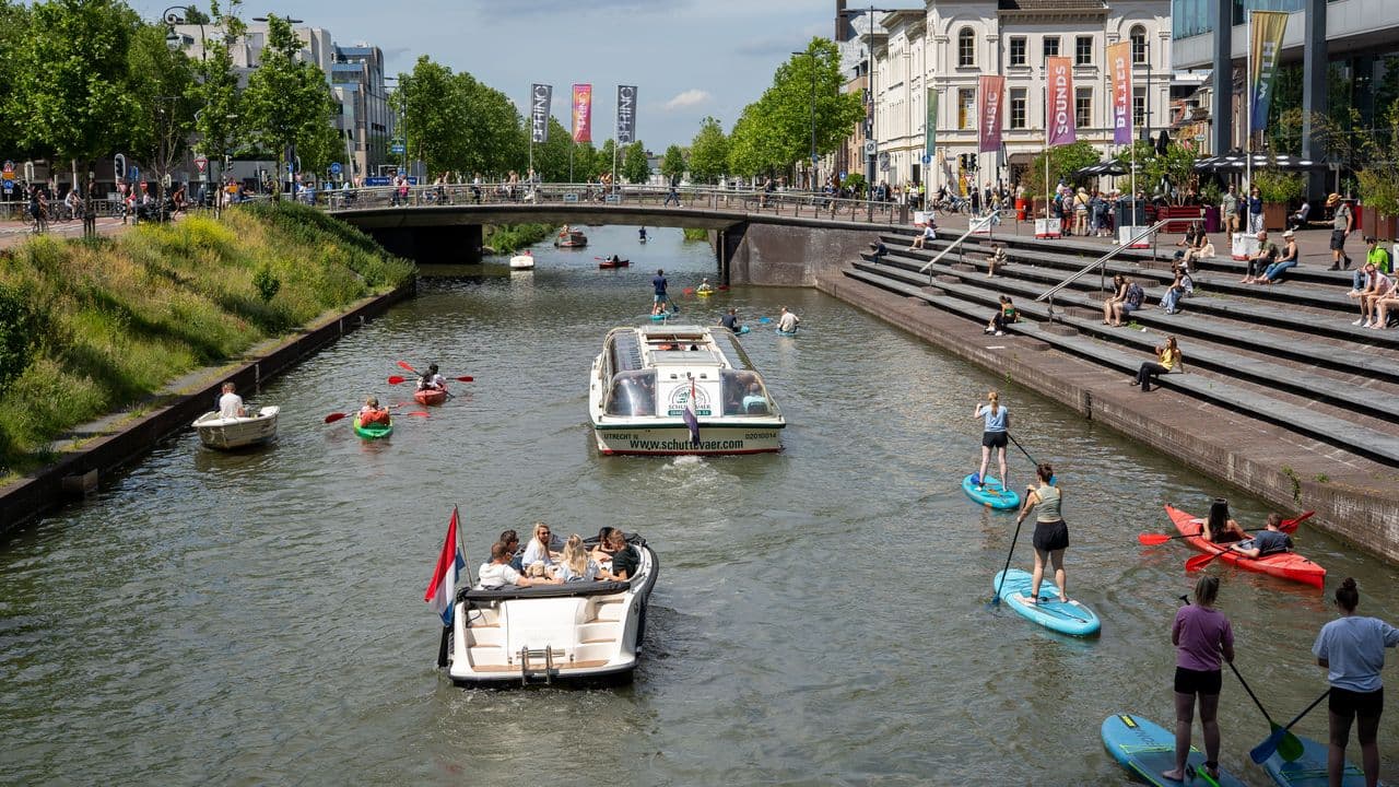 Canal concurrido con barcos, kayaks y practicantes de paddleboarding en Utrecht