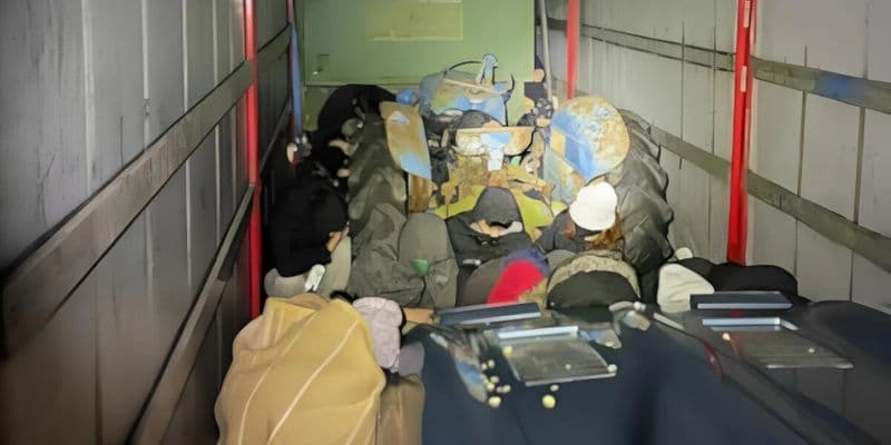 Un camión en un paso fronterizo con agentes de seguridad inspeccionando, destacando la captura del camionero holandés involucrado en el tráfico de personas.