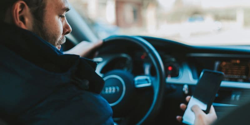 Persona conduciendo y mirando el teléfono