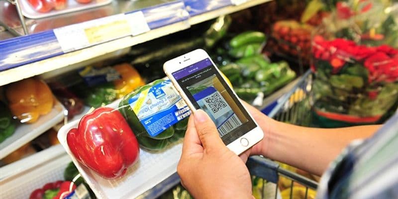 Persona escaneando un código QR en un envase de alimentos - Foto de Hữu Khoa en VietnamNiews