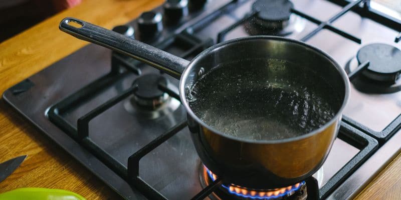 Persona hirviendo agua en un cazo en la cocina