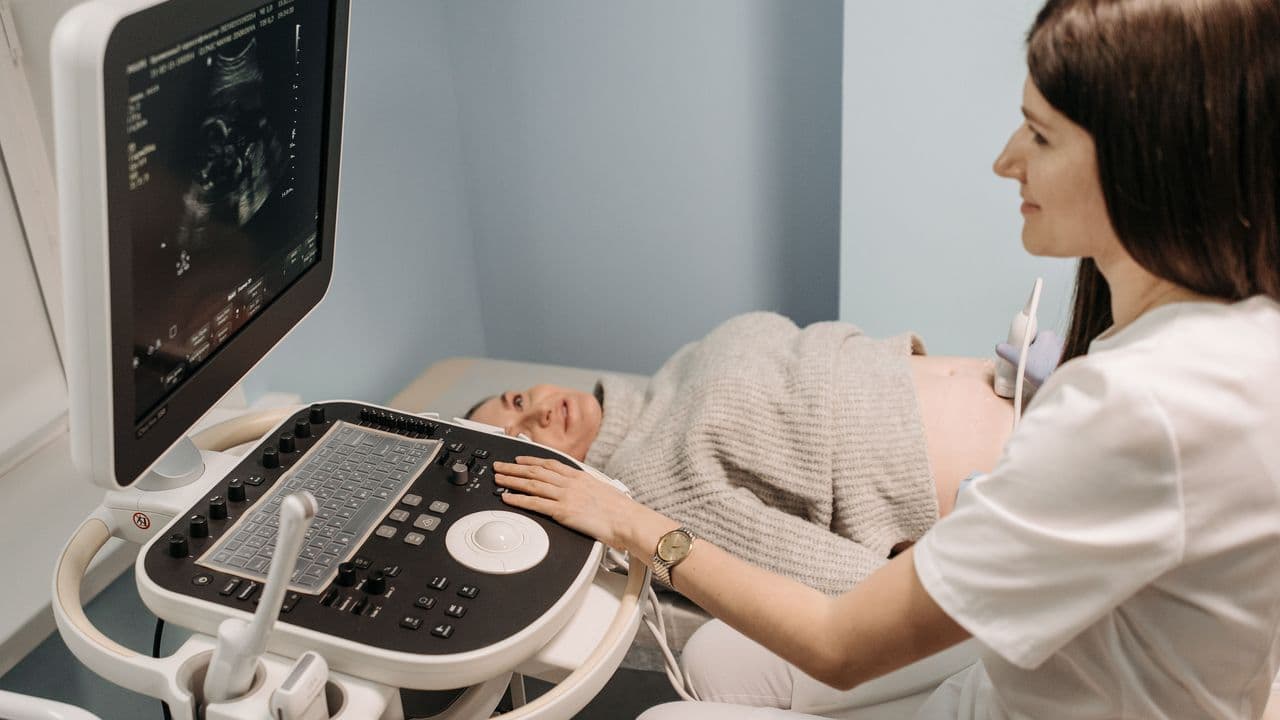 Una profesional sanitaria realiza una ecografía prenatal a una mujer embarazada