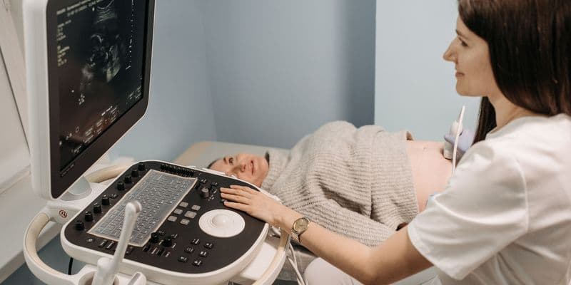 Una profesional sanitaria realiza una ecografía prenatal a una mujer embarazada