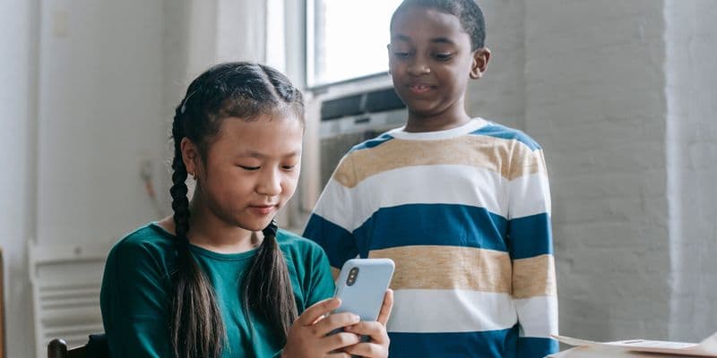 Un niño utiliza un smartphone mientras está sentado en un entorno escolar