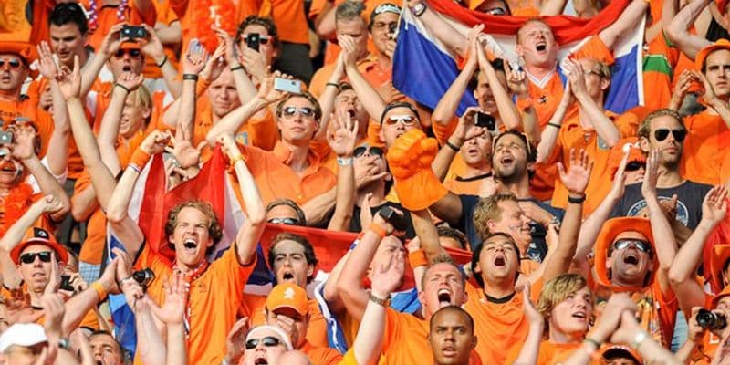 Aficionados holandeses de naranja con banderas y decoraciones, dirigiéndose hacia Hamburgo para el Campeonato de Europa.